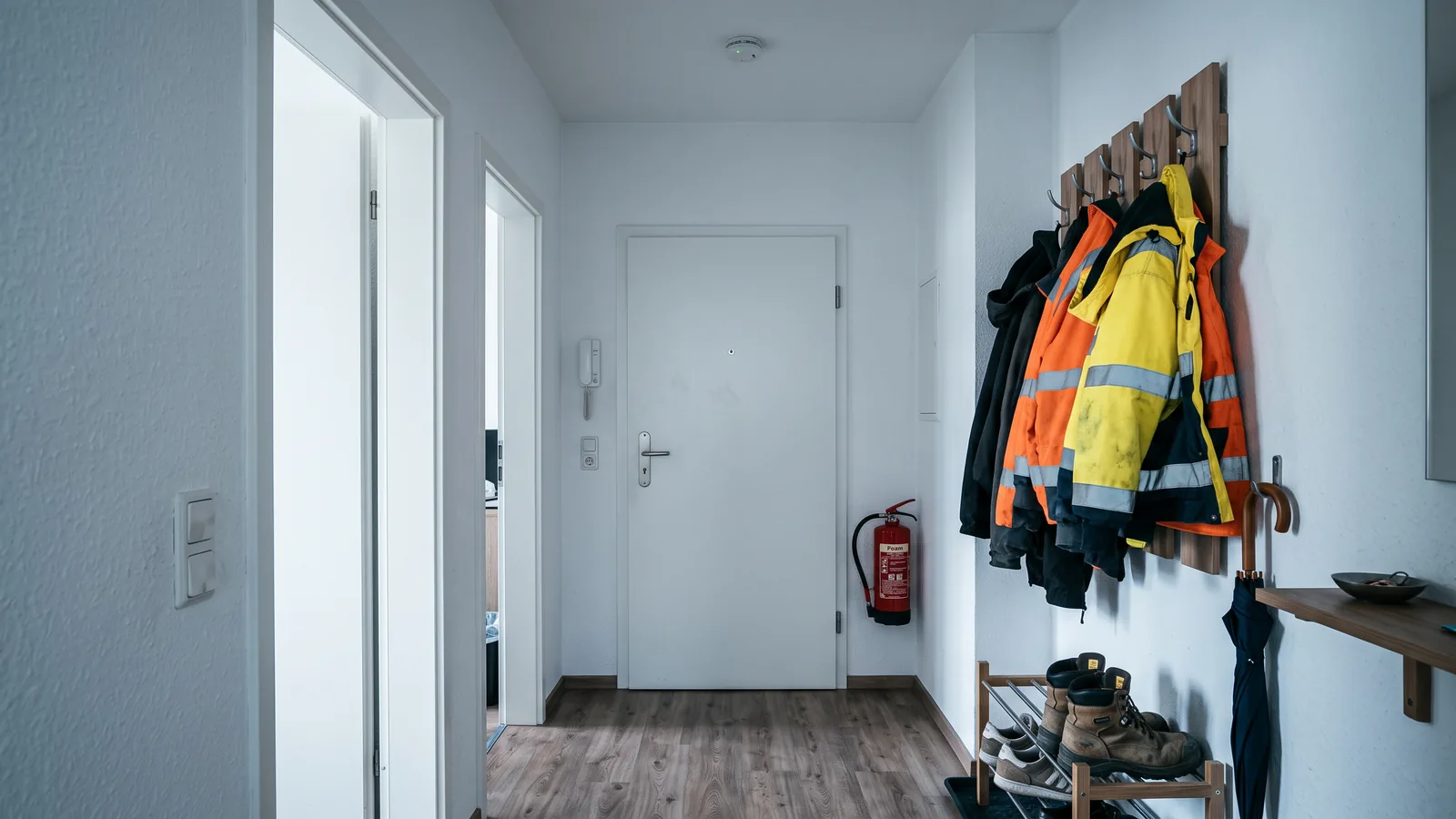 Flur einer Monteurwohnung mit Rauchwarnmelder an der Decke, Feuerlöscher an der Wand und freiem Fluchtweg zur Tür
