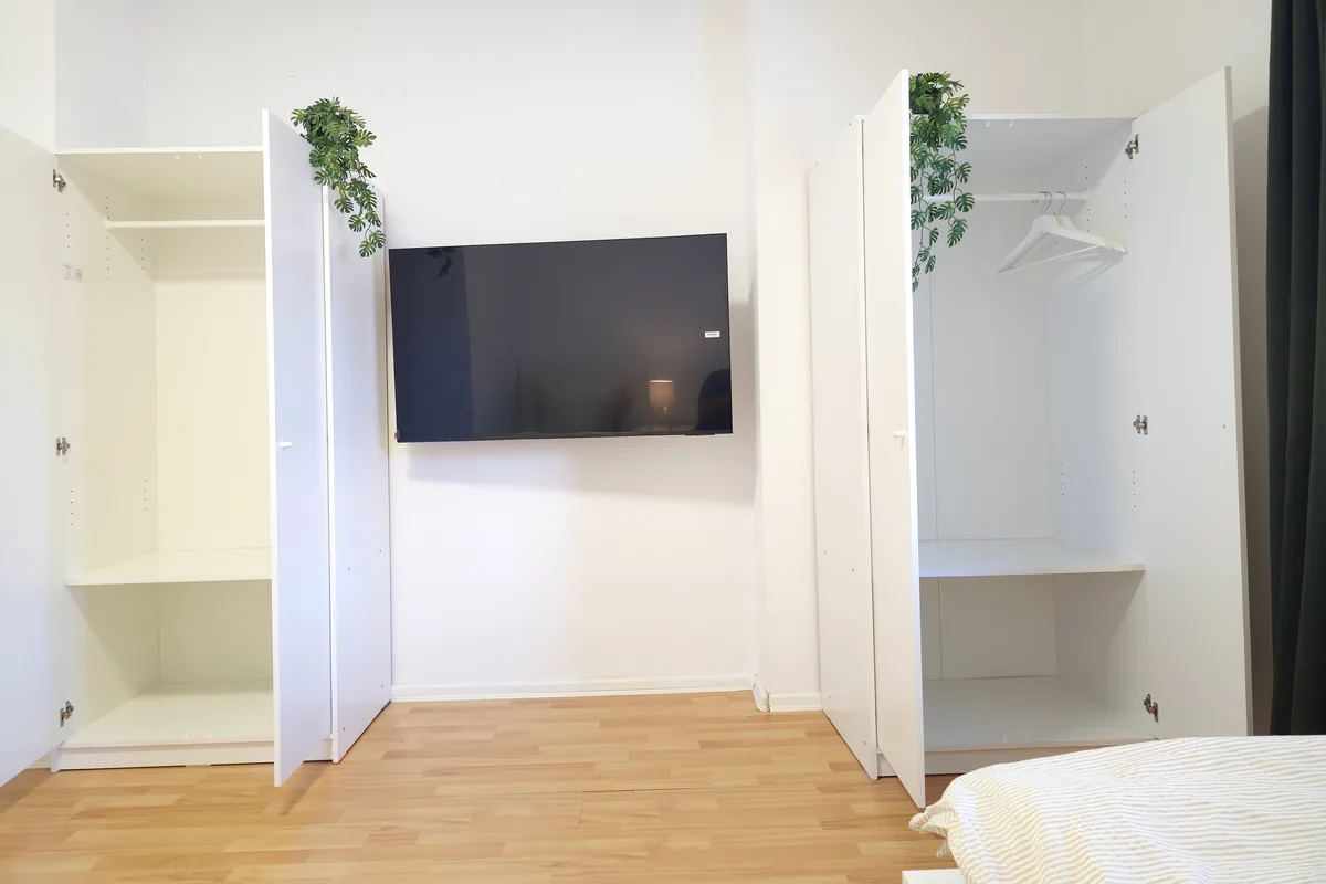 Offene Kleiderschränke und Fernseher als Teil des Inventars
