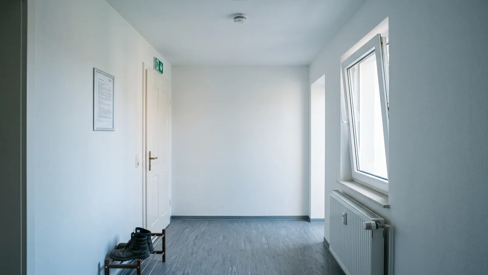 Flur einer Monteurunterkunft mit Rauchmelder, Hausordnung und Notausgangsschild