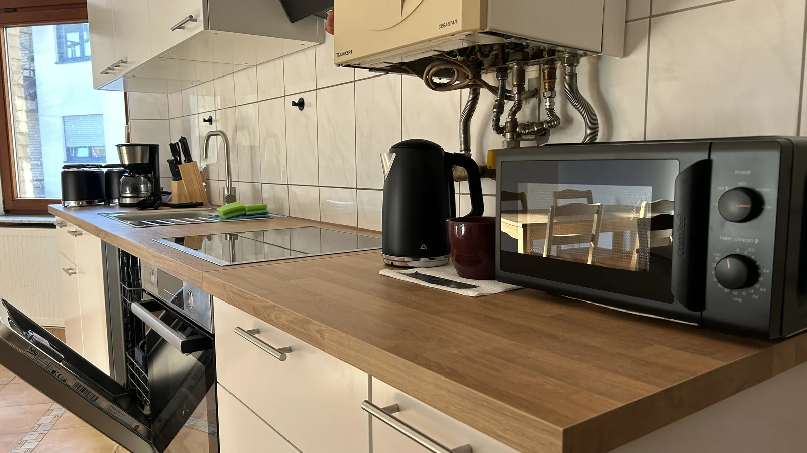 Küchenzeile mit Kaffeemaschine, Wasserkocher und Mikrowelle im Morgenlicht